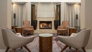 A modern lounge area with a fireplace, two armchairs, a round coffee table, and decorative plants. - Sonesta Select Seattle Bellevue Redmond (Bellevue)