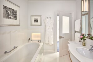 A modern bathroom with a freestanding bathtub, a vanity with a large mirror and sink, and a framed picture on the wall. - The Connaught, Maybourne  (London)