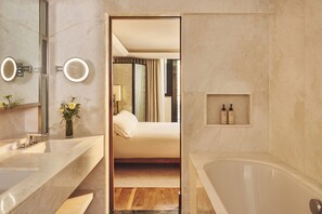 A modern bathroom with a large mirror, a bathtub, and a vanity with a sink.