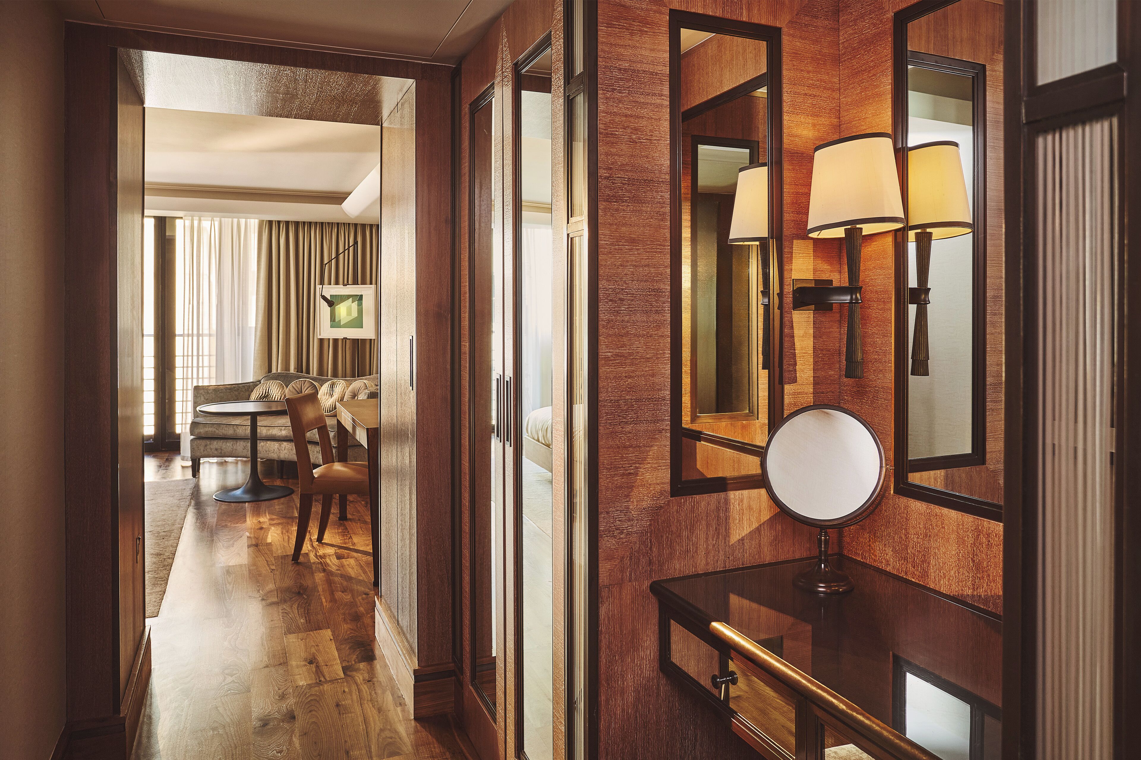 Ein Hotelkorridor mit Holzvertäfelung, einem runden Spiegel und einem Tisch mit Stühlen.