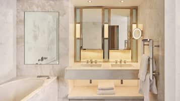 A modern bathroom with a bathtub, two sinks, a vanity, and a large mirror.