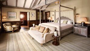 A four-poster bed with a canopy, a sofa, and a small table with a vase.