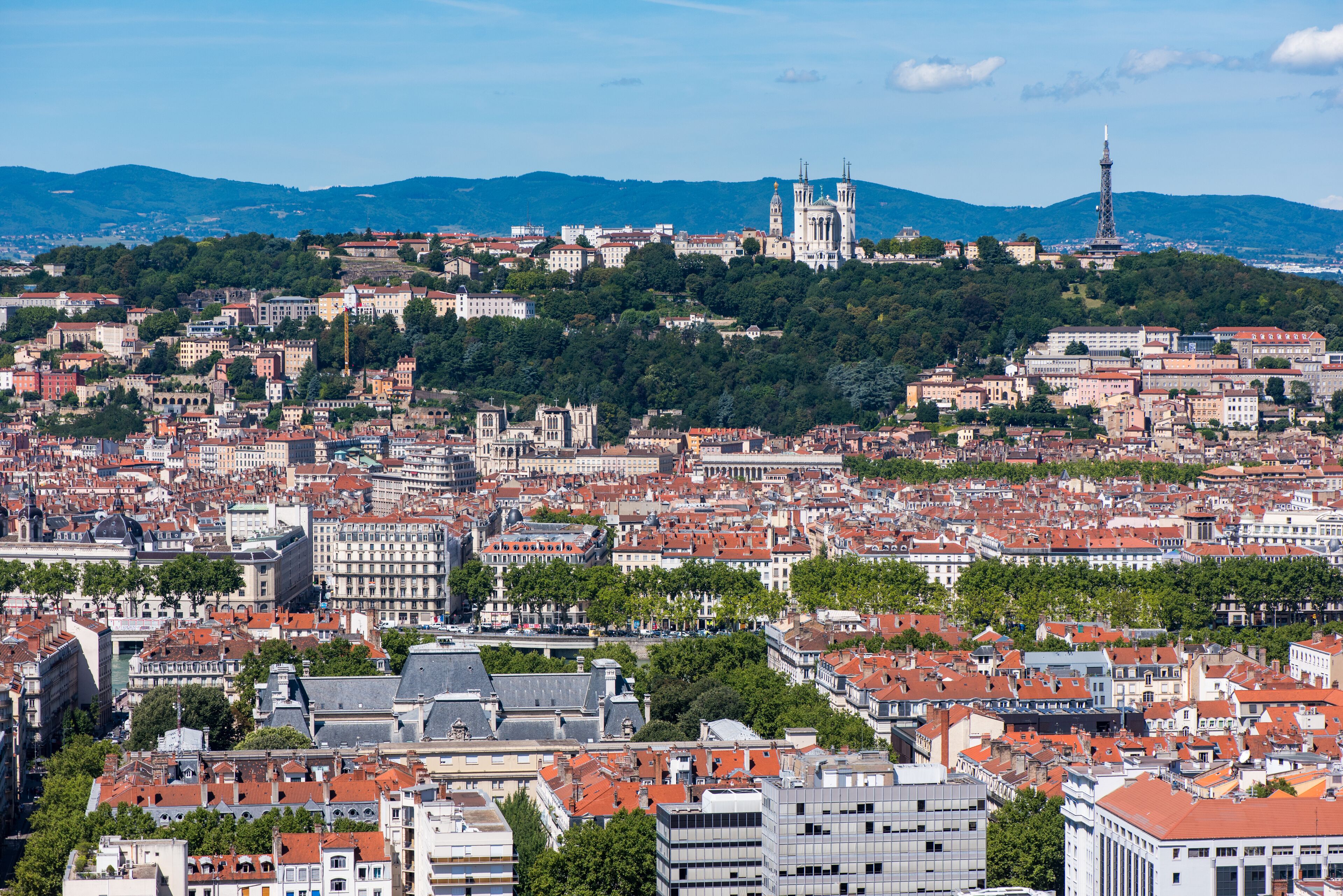A panoramic view of a cityscape with historic architecture, a prominent cathedral, and a tower.