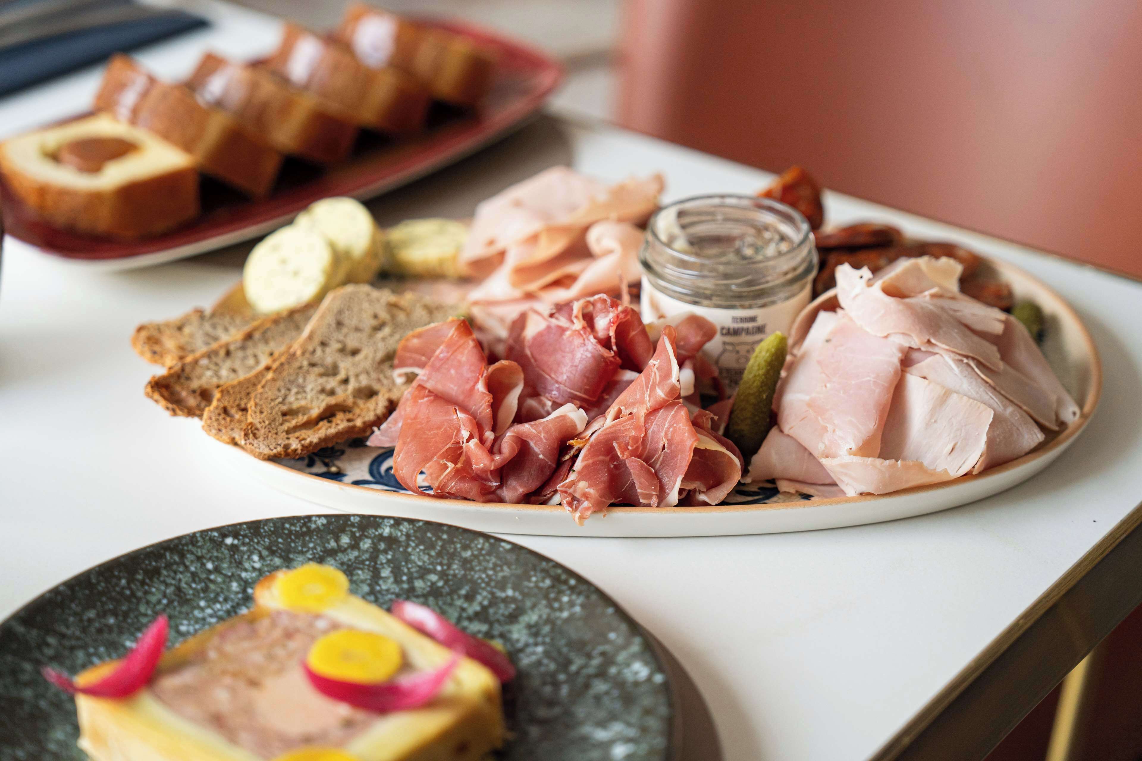 A table with various food items including bread, meats, and a small jar.