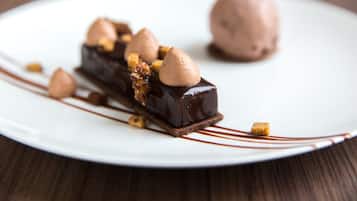 A dessert on a white plate with chocolate sauce and nuts.