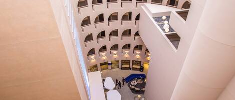 A multi-level atrium with a central seating area, multiple balconies, and a modern architectural design.