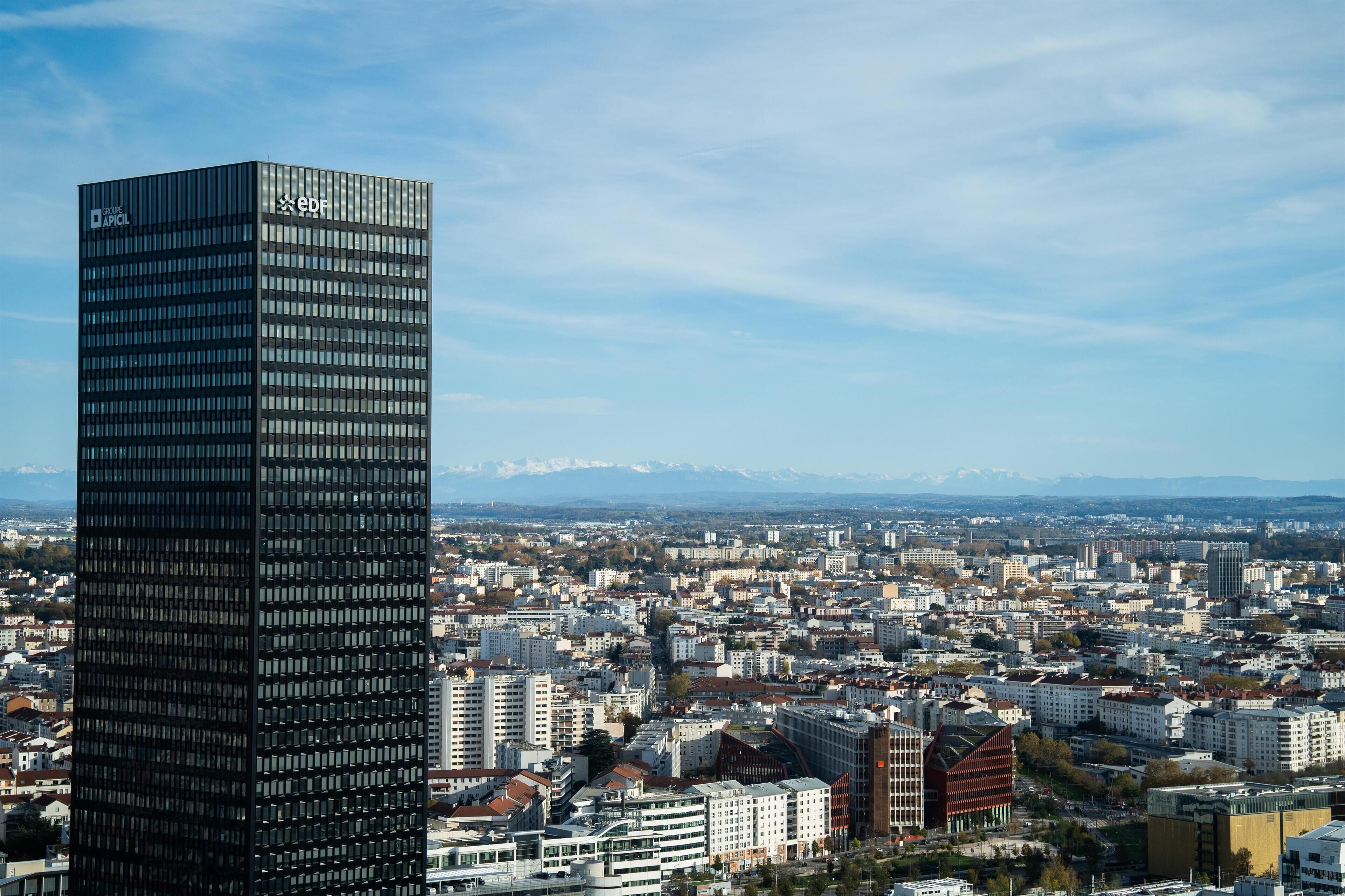 A high-rise building with a modern glass facade, surrounded by a densely packed urban area with various building styles.