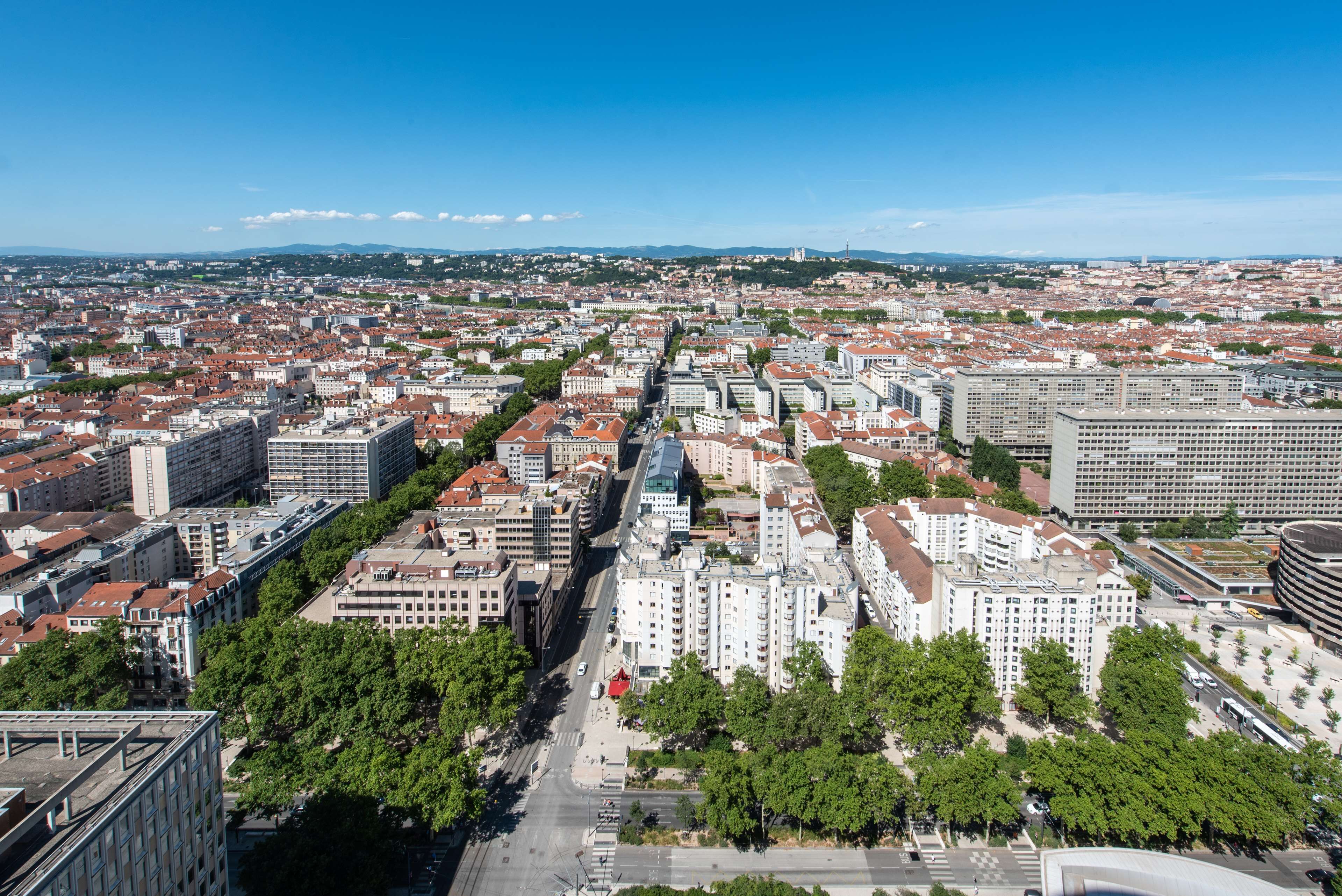 Un paisaje urbano con una mezcla de edificios modernos y tradicionales, calles anchas y zonas verdes.