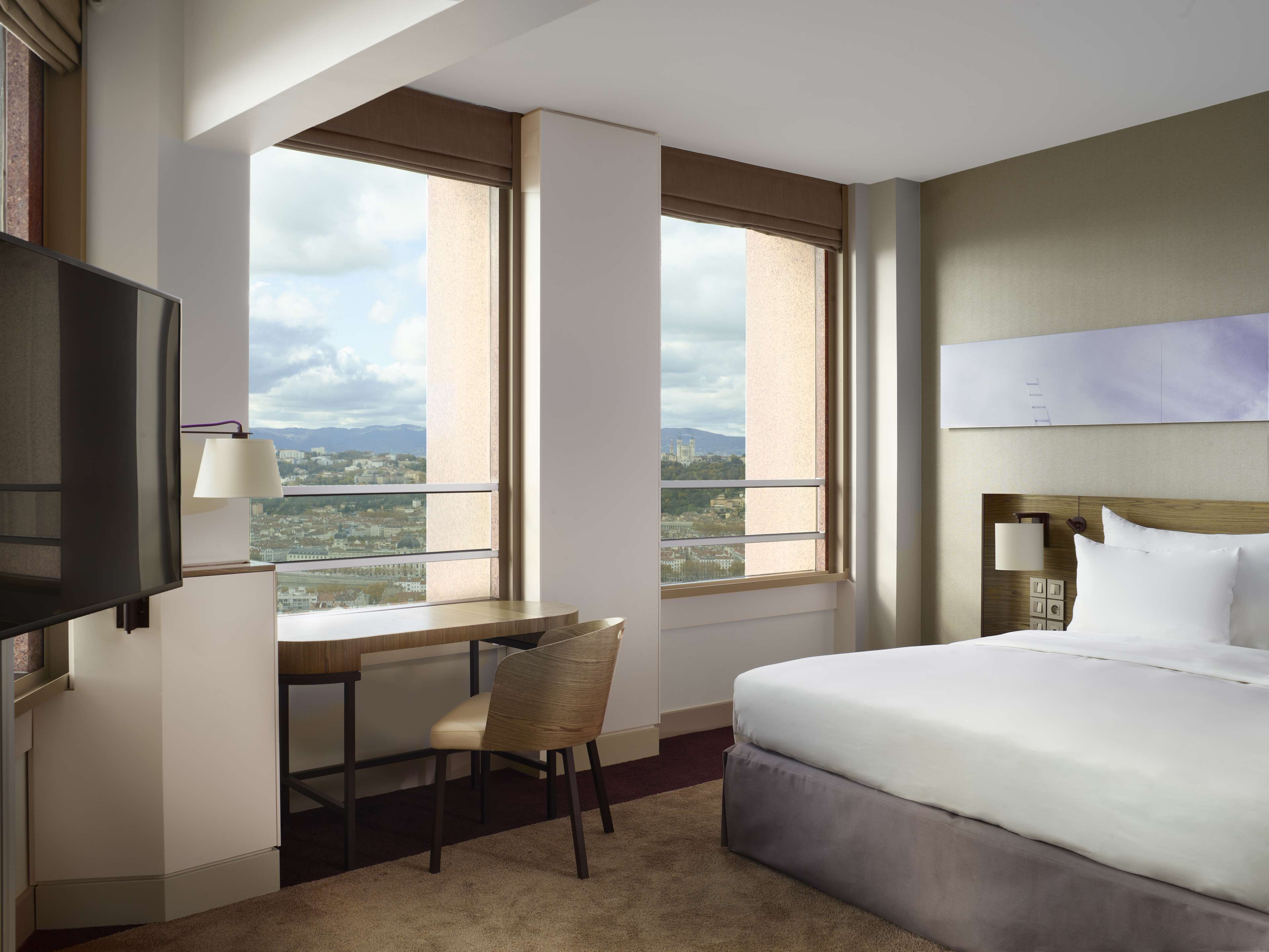 Une chambre d’hôtel avec un lit, un bureau, une chaise et un téléviseur.