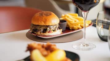 A meal consisting of a burger, fries, and a glass of red wine on a table.