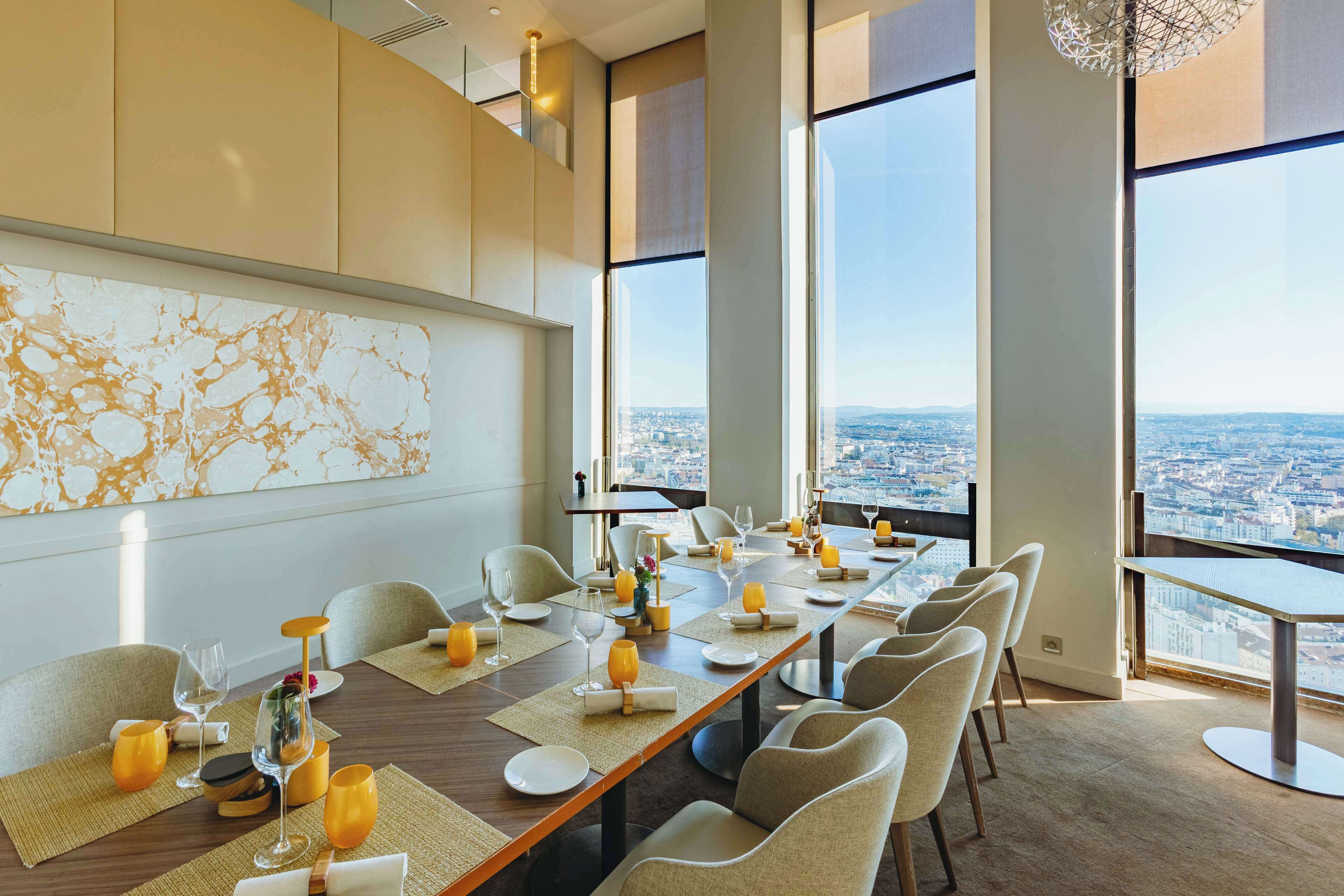 Une salle de conférence dotée d’une longue table, de chaises et offrant une vue sur la ville grâce à de grandes fenêtres.