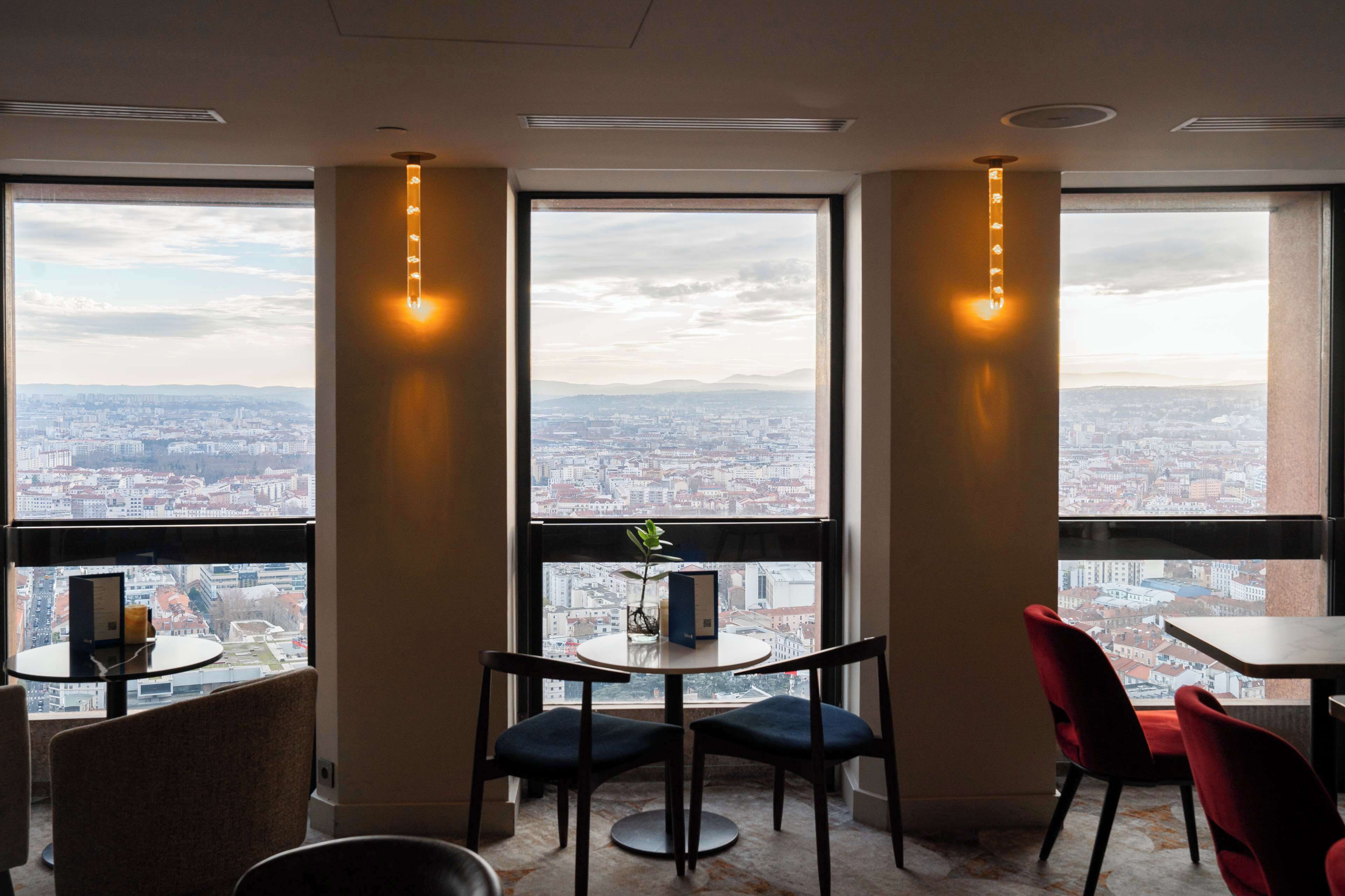 A modern room with large windows, a round table, and two chairs.