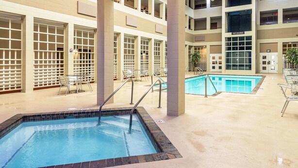 An indoor swimming pool with no diving signs, surrounded by a tiled floor and glass railings. - Quality Inn & Suites Virginia MN (Virginia)