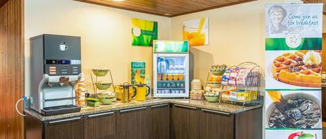 Un rincón para desayunar con cafetera, dispensador de zumo y mostrador refrigerado.