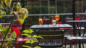 An outdoor seating area with tables and chairs, and two drinks on a table.