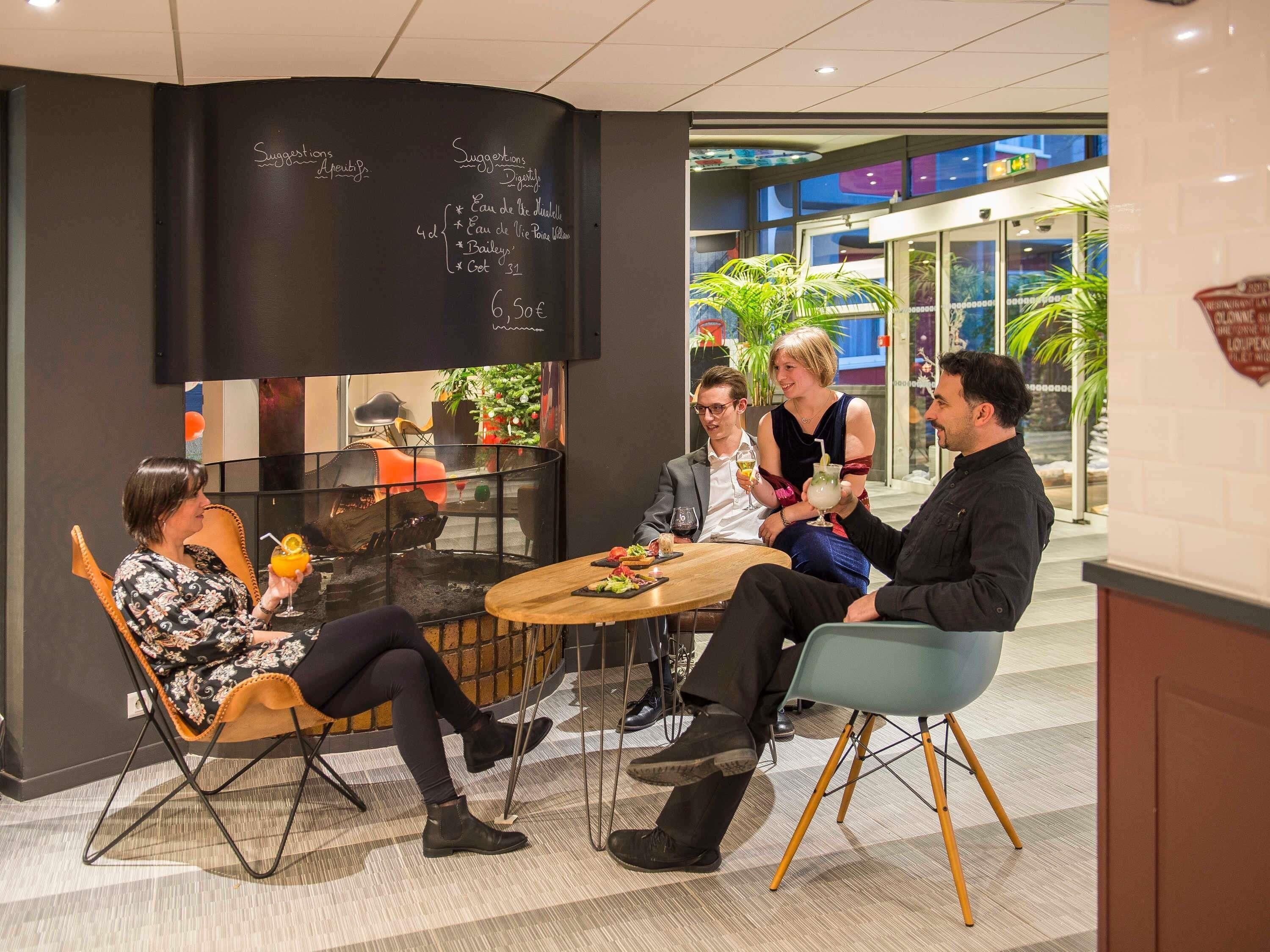 Un grupo de personas sentadas alrededor de una mesa en un ambiente interior moderno con una pizarra mostrando sugerencias del menú.