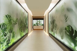 A hallway with a long, narrow layout, flanked by walls with tropical plant murals.