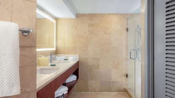 Un baño moderno con piso de mármol, cabina de ducha de vidrio y tocador con espejo y perchero.