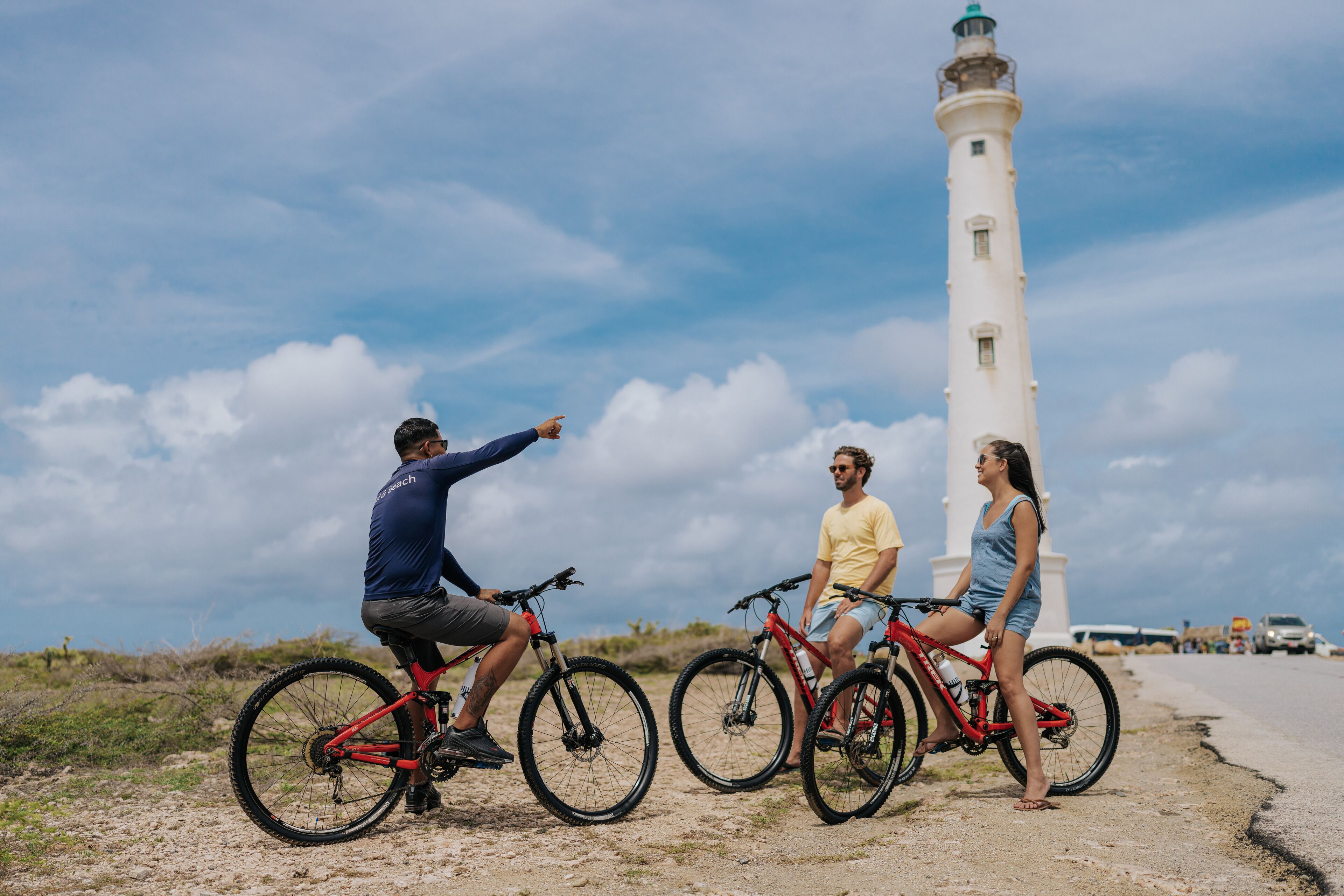 Tres personas en bicicleta cerca de un faro.