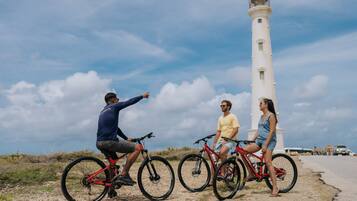 Tres personas en bicicleta cerca de un faro.