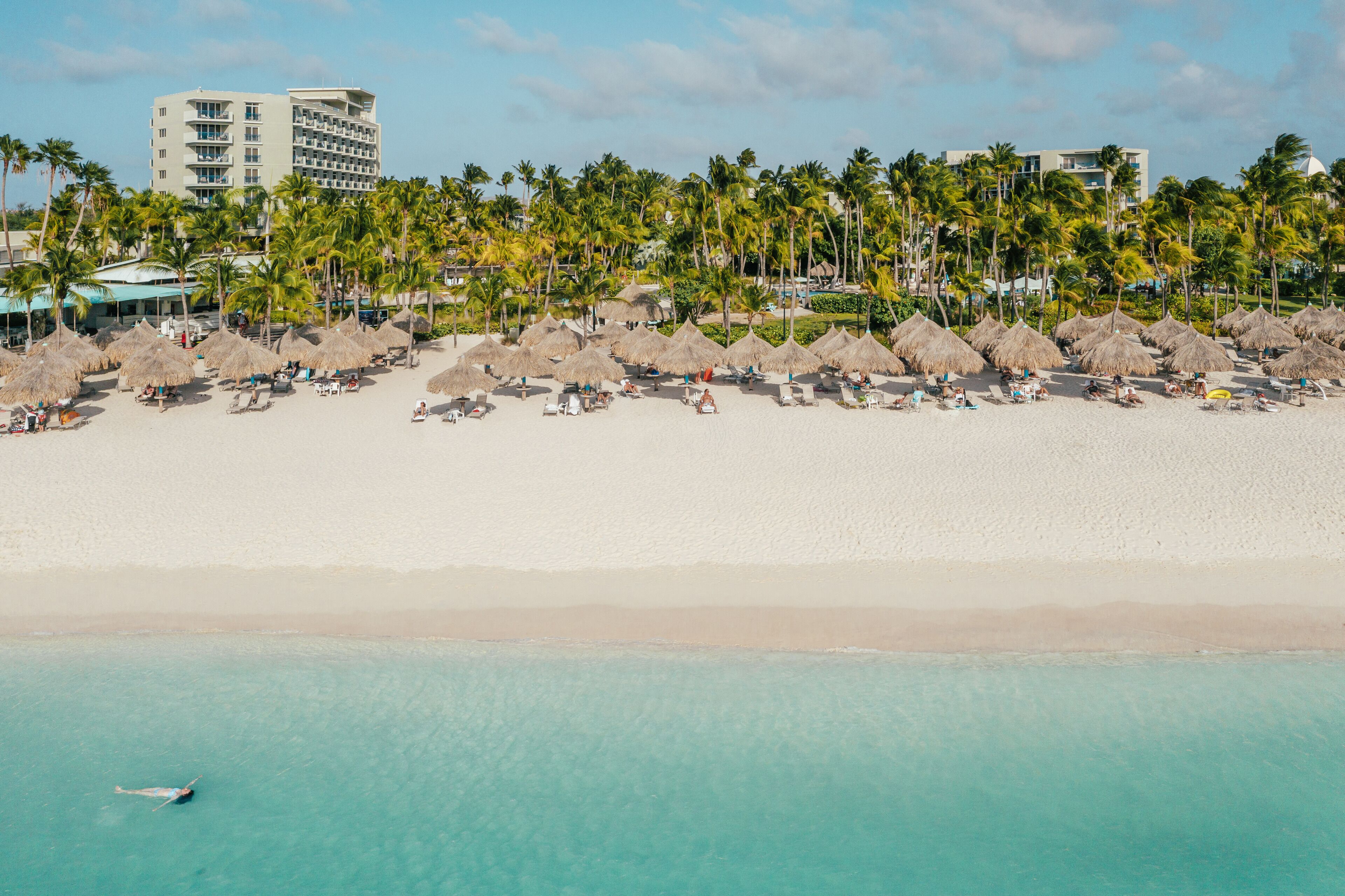A beach resort with thatched umbrellas, palm trees, and beachfront villas.
