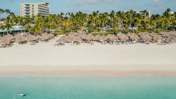 A beach resort with thatched umbrellas, palm trees, and beachfront villas.