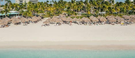 A beach resort with thatched umbrellas, palm trees, and beachfront villas.