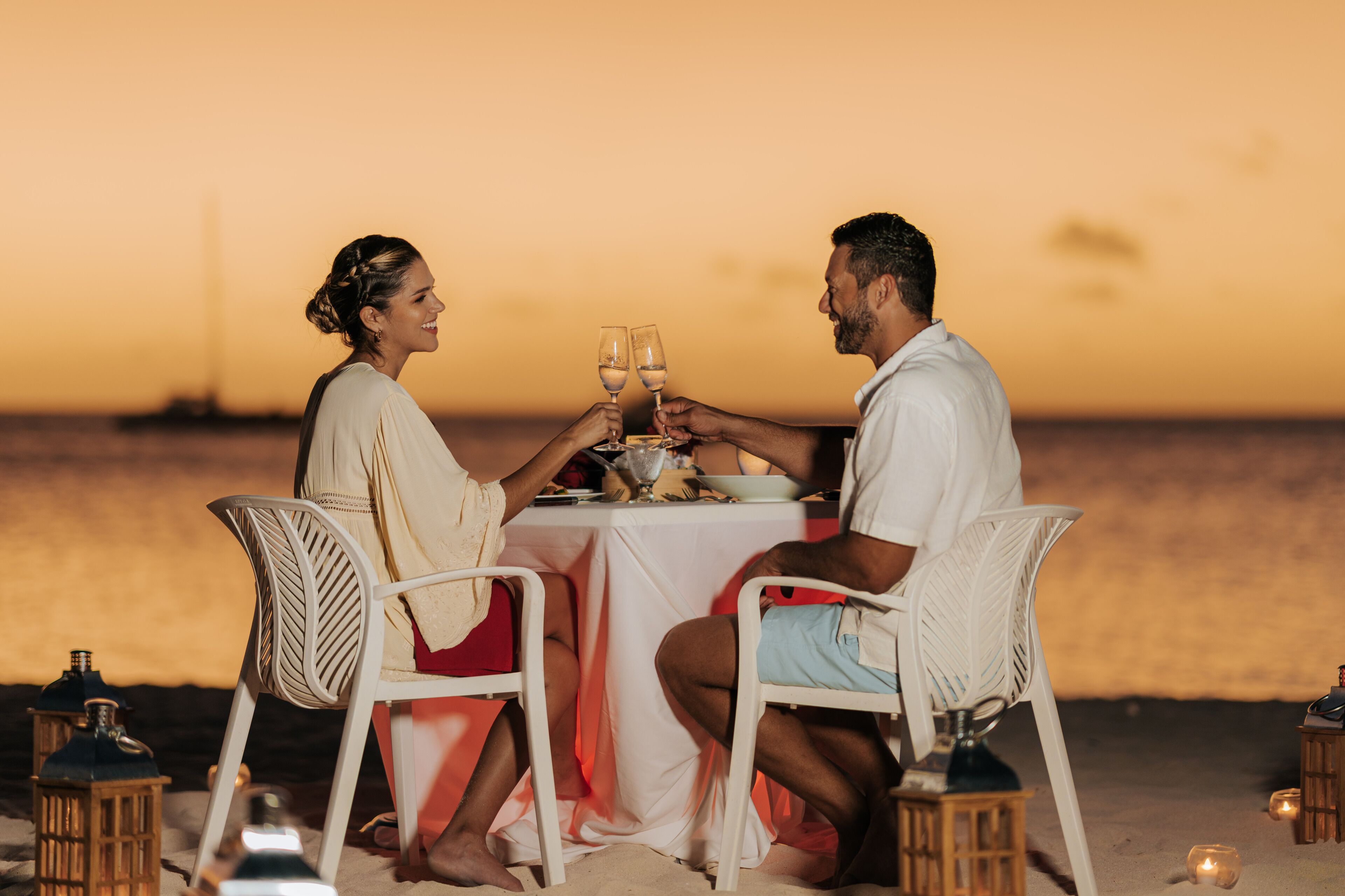 A couple dining at a table with a view of the ocean at sunset.