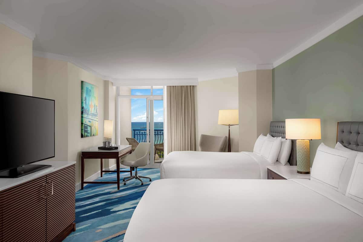 A hotel room with two beds, a TV, a desk, and a chair.