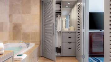 A modern bathroom with a bathtub, a walk-in closet, and a television.