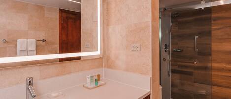 A modern bathroom with a large mirror, a sink, a toilet, and a glass-enclosed shower.