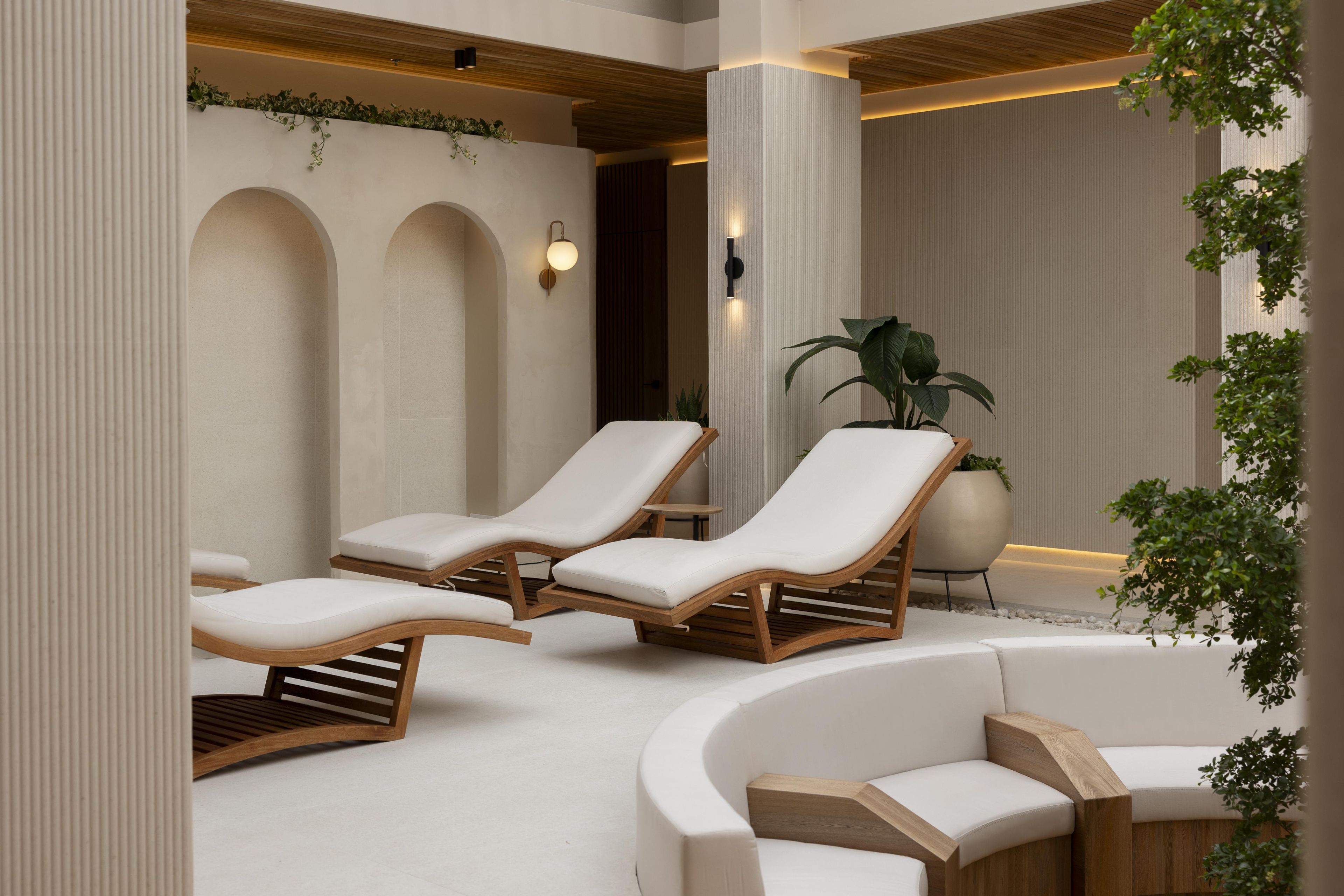 A spa area with two lounge chairs, a wooden bench, and a potted plant.