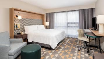 Habitación de hotel con una cama, un escritorio, una silla, un teléfono, una lámpara y un televisor.
