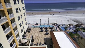 A rooftop pool area with lounge chairs and umbrellas, overlooking a beach with umbrellas and lounge chairs. - Residence Inn by Marriott Daytona Beach Oceanfront (Daytona Beach Shores)