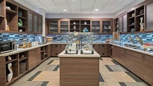 A modern kitchen with wooden cabinets, a central island, and a tiled backsplash. - Residence Inn by Marriott Daytona Beach Oceanfront (Daytona Beach Shores)