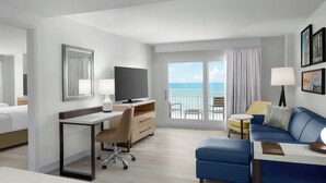 A hotel room with a bed, desk, chair, sofa, and a balcony with a view of the sea. - Residence Inn by Marriott Daytona Beach Oceanfront (Daytona Beach Shores)
