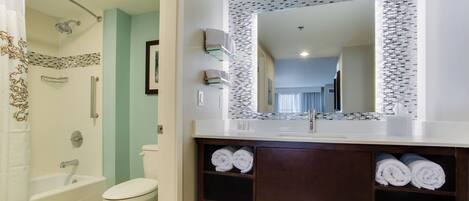 Un baño moderno con bañera, inodoro y tocador con espejo.
