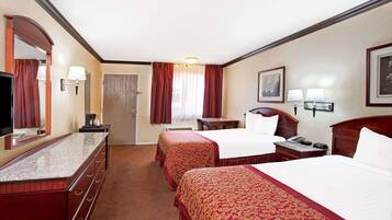 A hotel room with two beds, a desk, a chair, a television, and a door.