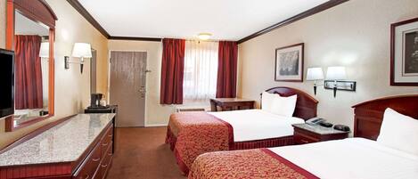 Habitación de hotel con dos camas, un escritorio, una silla, un televisor y una puerta.