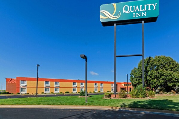 Un hôtel Quality Inn avec un ciel bleu dégagé, un parking et une pelouse bien entretenue.