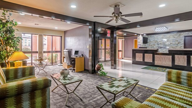 A hotel lobby with a reception desk, seating area, and a desk with a computer.
