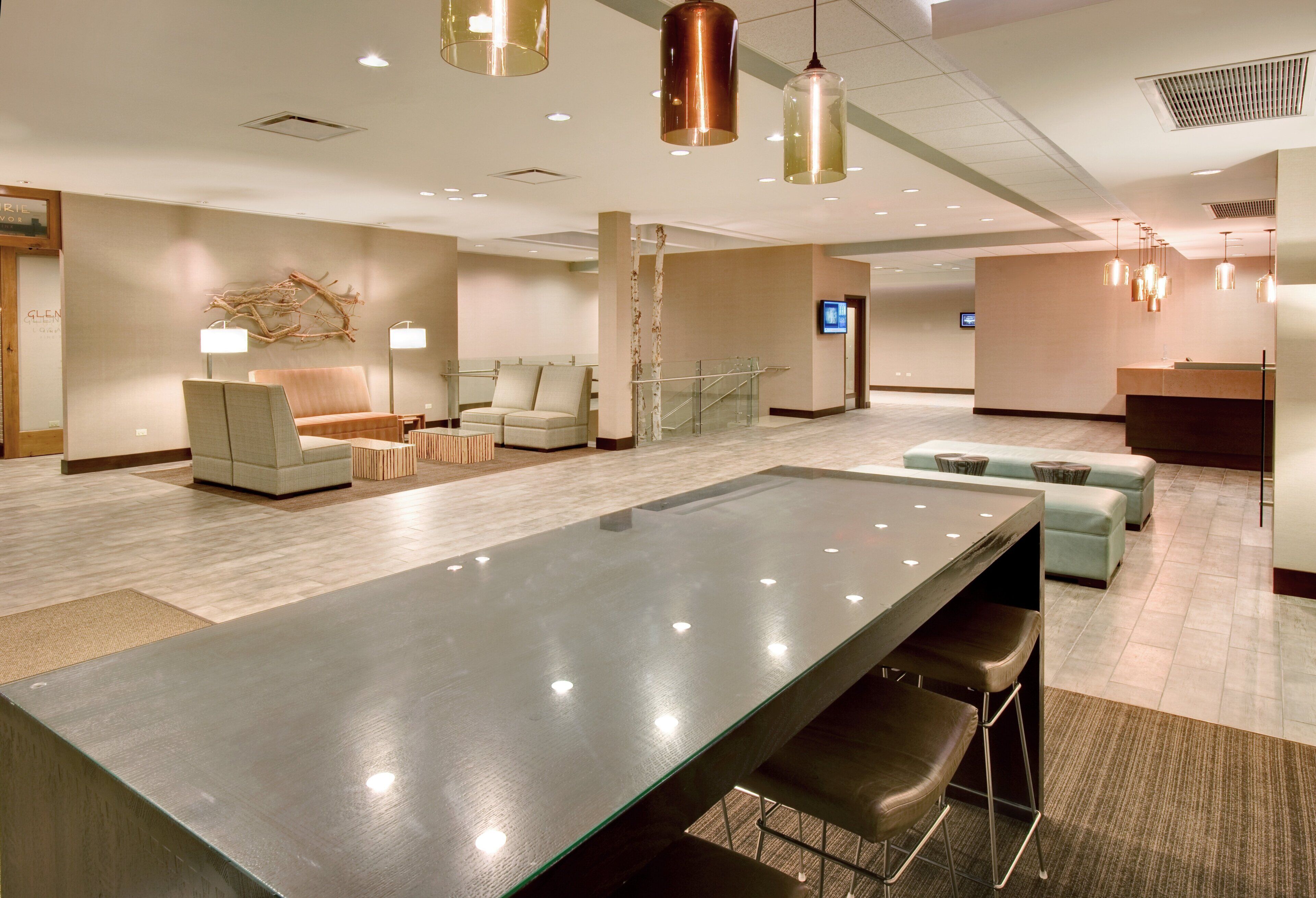 A spacious lobby with a long reception desk, seating areas, and modern lighting fixtures.