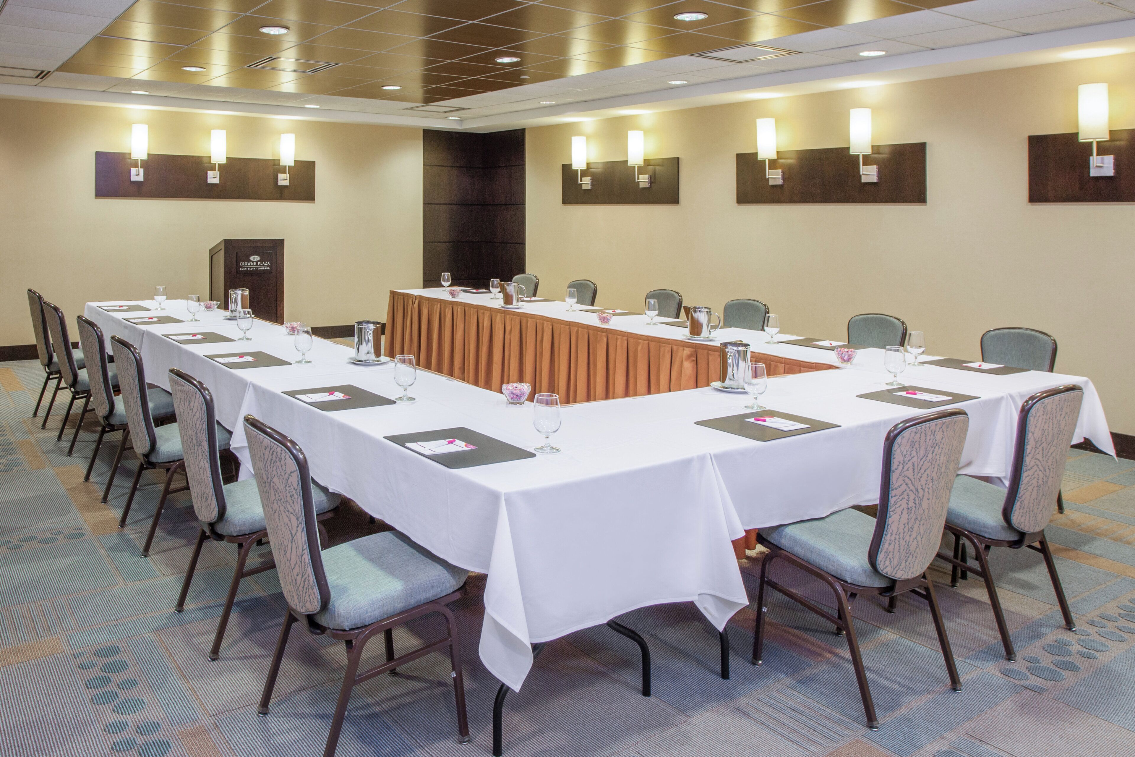 Uma sala de conferência com uma mesa comprida, cadeiras e um pódio.