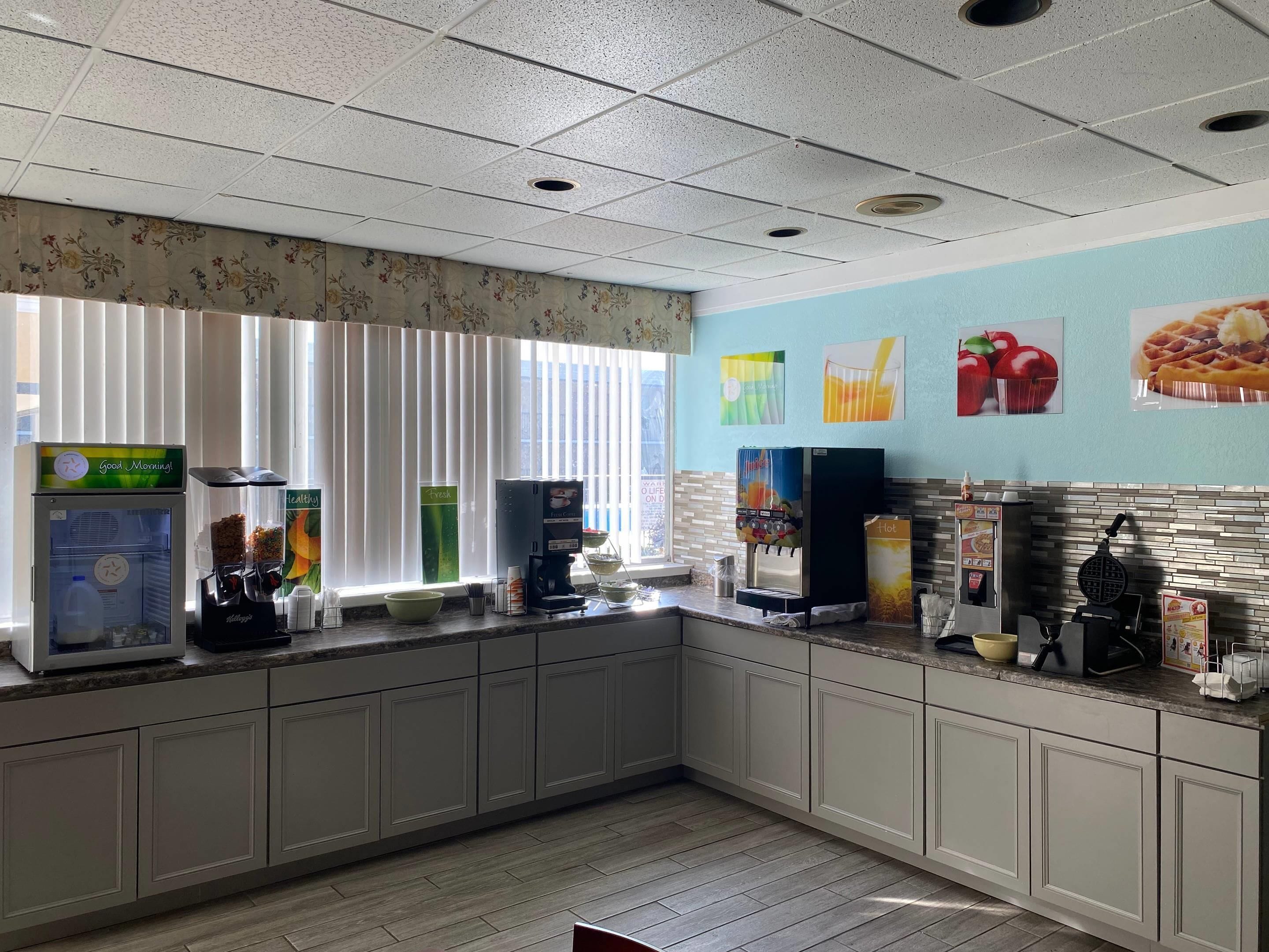 A kitchen area with a coffee machine, a juice dispenser, and a waffle maker.