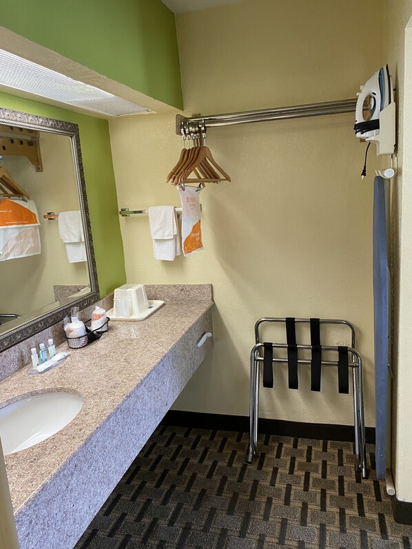 A bathroom with a sink, mirror, towel rack, and shower area.