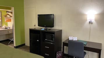 Ett hotellrum med en säng, ett skrivbord med en dator, en tv och en papperskorg.
