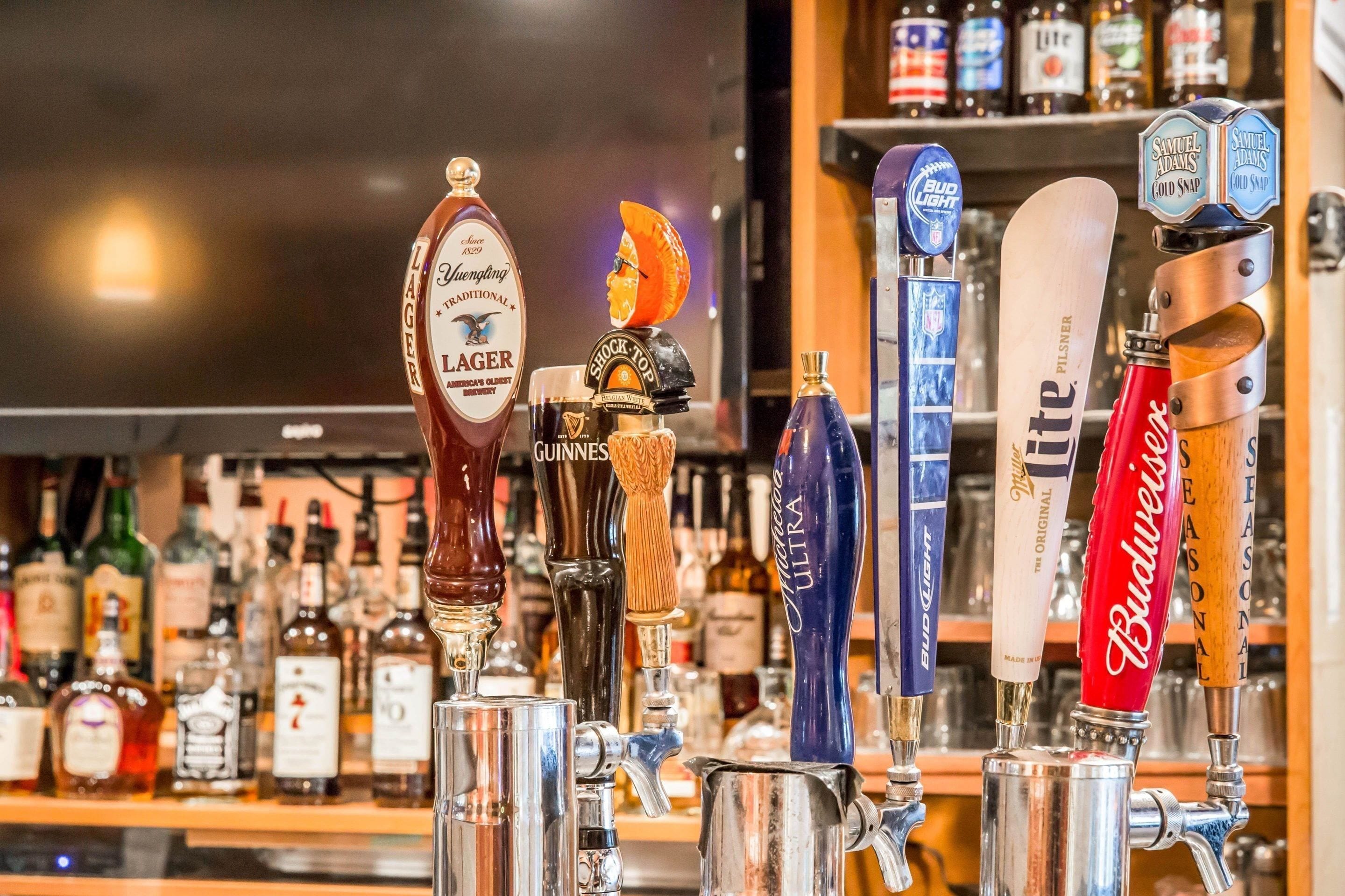 A bar with various beer taps including brands like Guinness, Budweiser, and Samuel Adams.