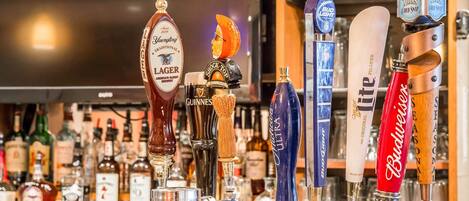 Un bar con varias griferías de cerveza, incluyendo marcas como Guinness, Budweiser y Samuel Adams.