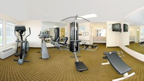 Un gimnasio con equipo de ejercicio diverso, una banca y un espejo grande.