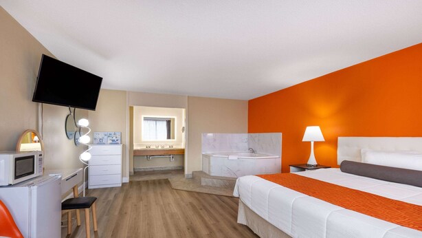 Ein Hotelzimmer mit Bett, Schreibtisch, Fernseher, Badezimmer und Fenster.
